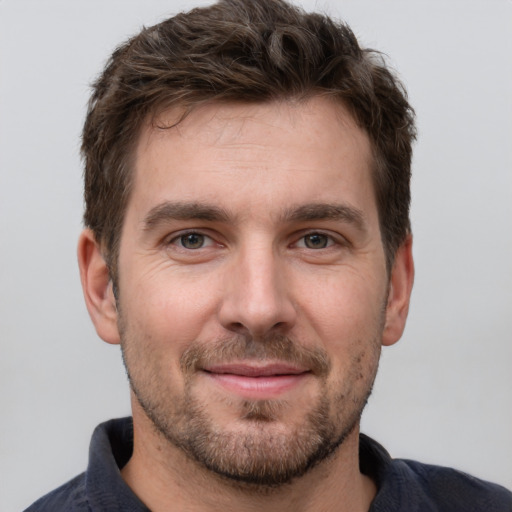 Joyful white young-adult male with short  brown hair and grey eyes