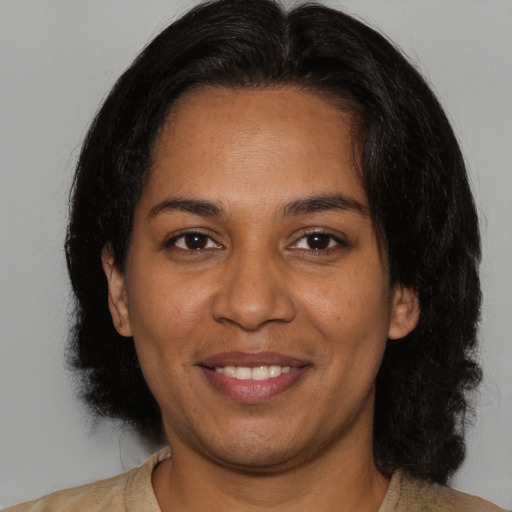 Joyful black young-adult female with long  brown hair and brown eyes