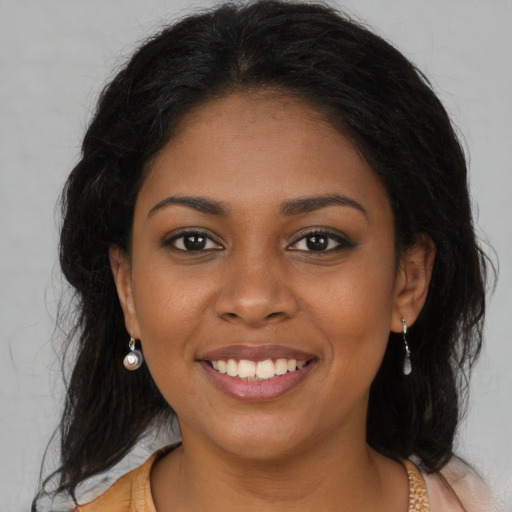 Joyful black young-adult female with long  brown hair and brown eyes