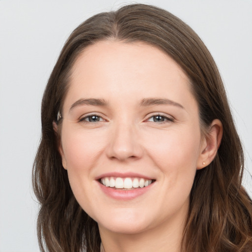 Joyful white young-adult female with long  brown hair and grey eyes