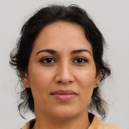 Joyful latino adult female with medium  brown hair and brown eyes