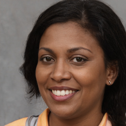 Joyful black young-adult female with long  brown hair and brown eyes