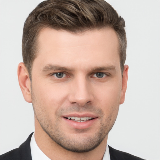 Joyful white young-adult male with short  brown hair and grey eyes