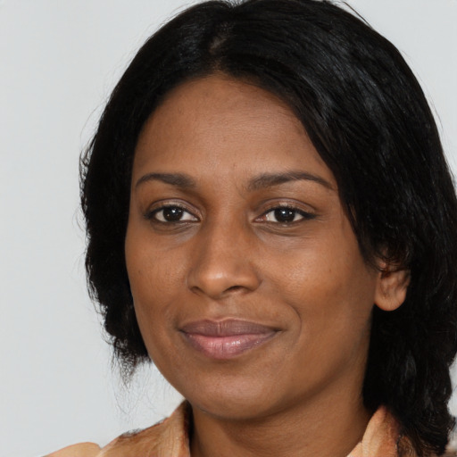 Joyful black young-adult female with long  black hair and brown eyes