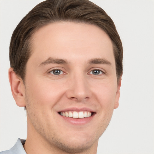 Joyful white young-adult male with short  brown hair and grey eyes