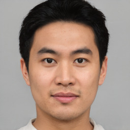 Joyful asian young-adult male with short  black hair and brown eyes