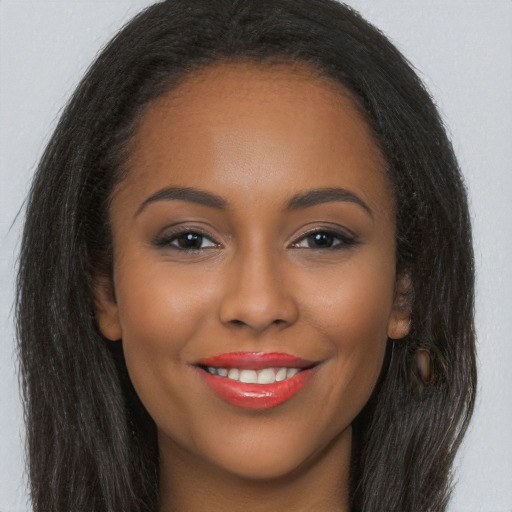 Joyful black young-adult female with long  brown hair and brown eyes