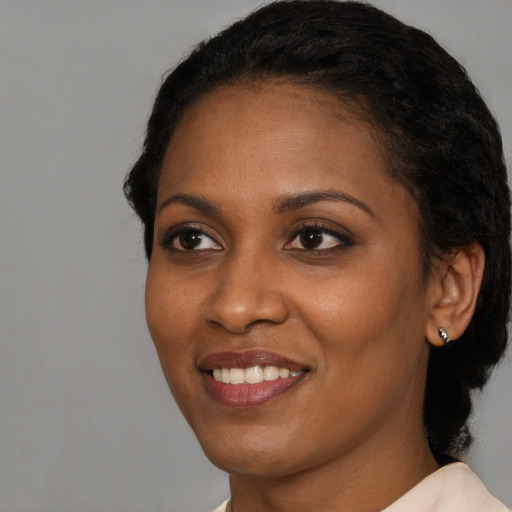 Joyful black young-adult female with short  black hair and brown eyes