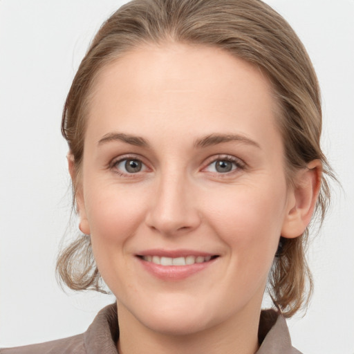 Joyful white young-adult female with medium  brown hair and grey eyes