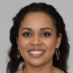 Joyful black young-adult female with long  brown hair and brown eyes