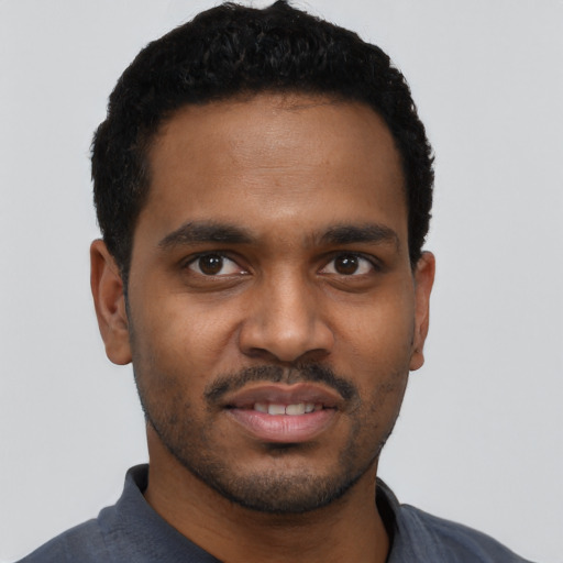 Joyful black young-adult male with short  black hair and brown eyes