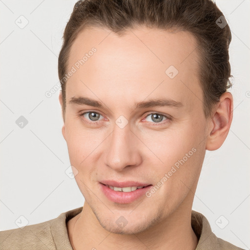 Joyful white young-adult male with short  brown hair and grey eyes