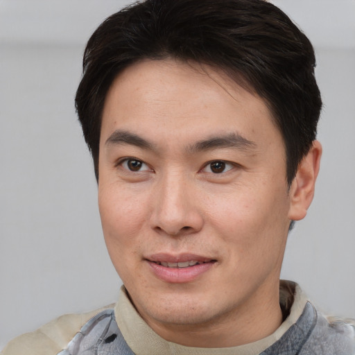 Joyful asian young-adult male with short  brown hair and brown eyes