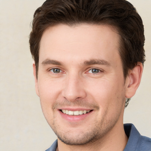 Joyful white young-adult male with short  brown hair and grey eyes