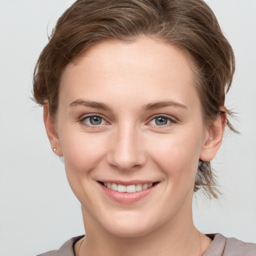 Joyful white young-adult female with medium  brown hair and grey eyes