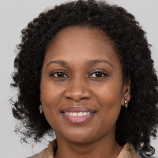 Joyful black adult female with long  brown hair and brown eyes