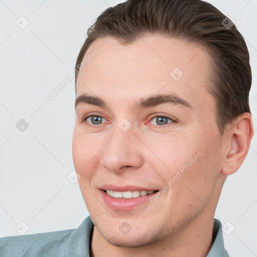 Joyful white young-adult male with short  brown hair and grey eyes