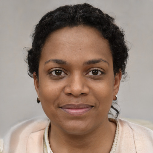 Joyful black young-adult female with short  black hair and brown eyes