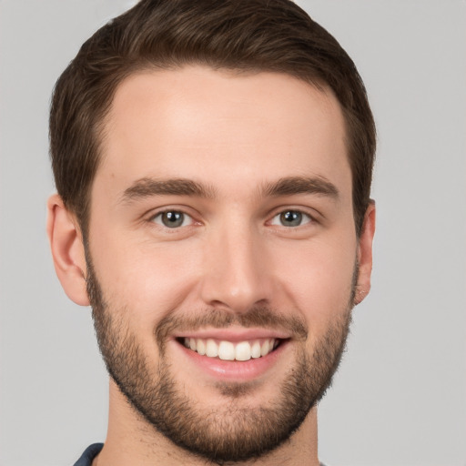 Joyful white young-adult male with short  brown hair and grey eyes