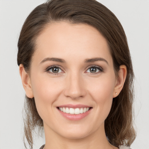 Joyful white young-adult female with medium  brown hair and grey eyes