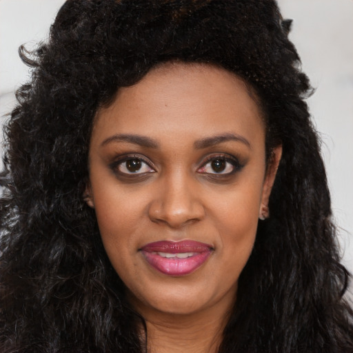 Joyful black young-adult female with long  black hair and brown eyes