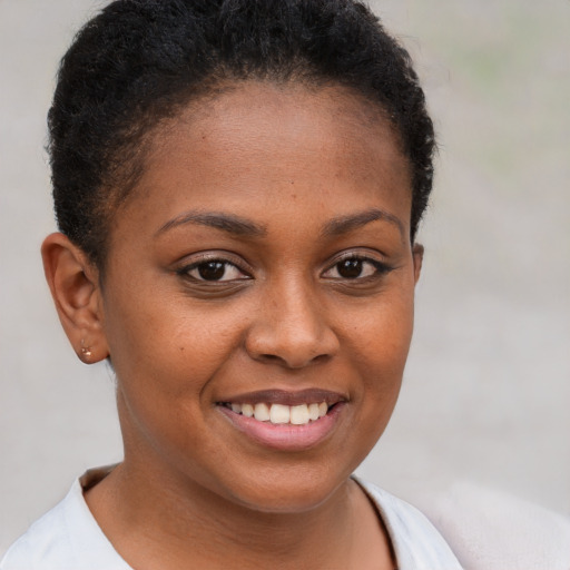 Joyful black young-adult female with short  brown hair and brown eyes