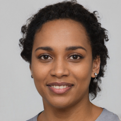 Joyful black young-adult female with short  black hair and brown eyes