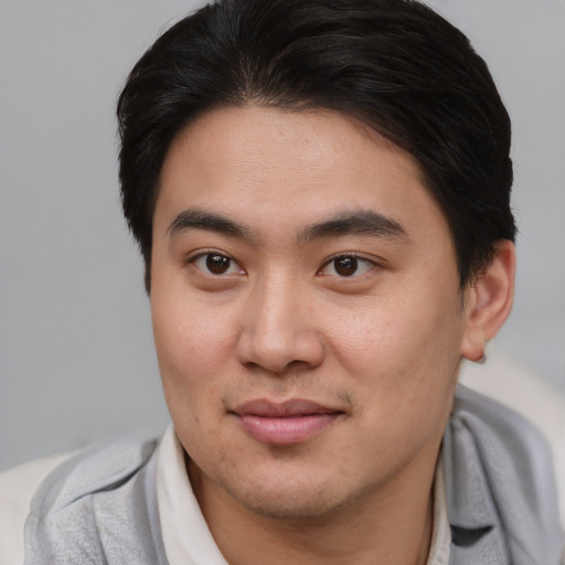 Joyful asian young-adult male with short  brown hair and brown eyes