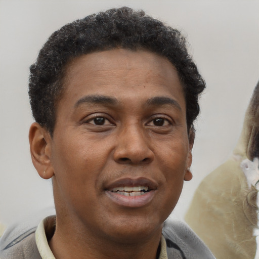 Joyful black young-adult male with short  brown hair and brown eyes