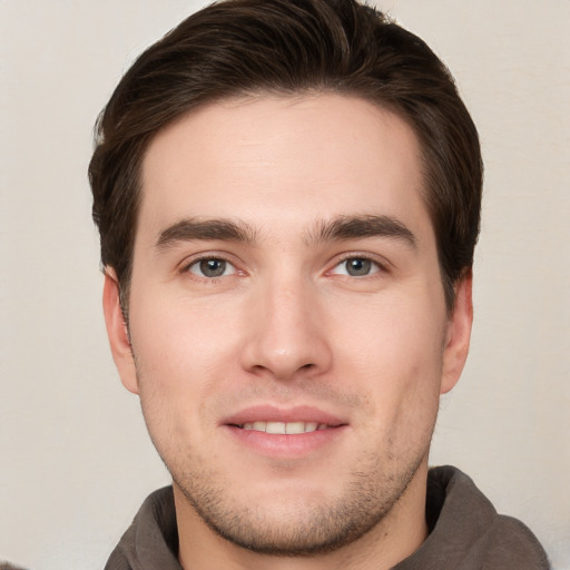 Joyful white young-adult male with short  brown hair and grey eyes