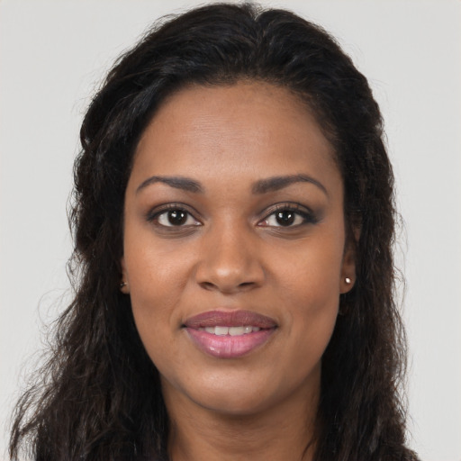 Joyful black young-adult female with long  brown hair and brown eyes