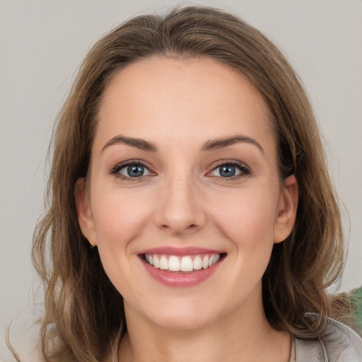 Joyful white young-adult female with long  brown hair and grey eyes