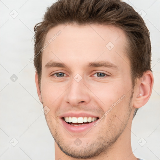 Joyful white young-adult male with short  brown hair and grey eyes