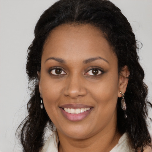 Joyful black young-adult female with long  brown hair and brown eyes