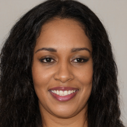 Joyful black young-adult female with long  brown hair and brown eyes