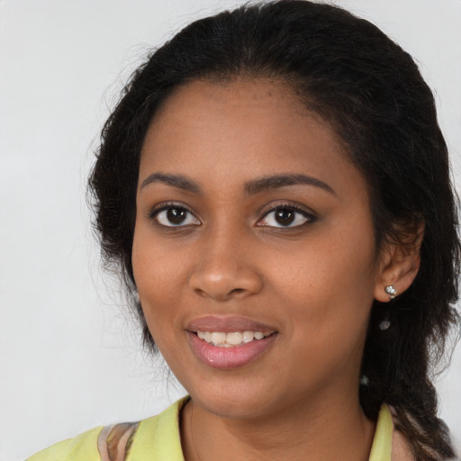 Joyful black young-adult female with long  brown hair and brown eyes