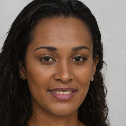 Joyful black young-adult female with long  brown hair and brown eyes