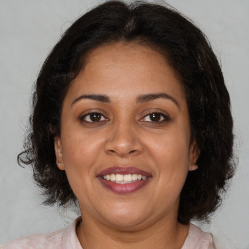 Joyful latino adult female with medium  brown hair and brown eyes