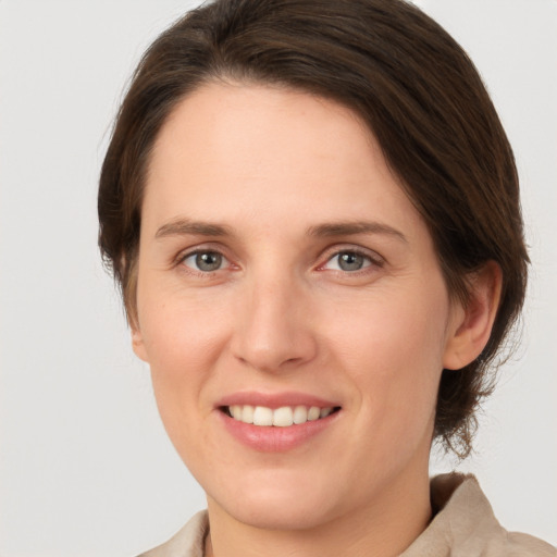 Joyful white young-adult female with medium  brown hair and grey eyes