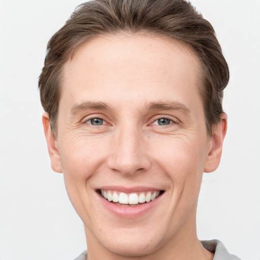 Joyful white young-adult male with short  brown hair and grey eyes