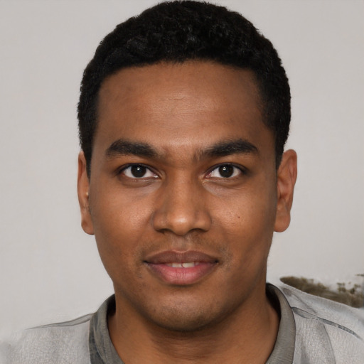 Joyful black young-adult male with short  black hair and brown eyes