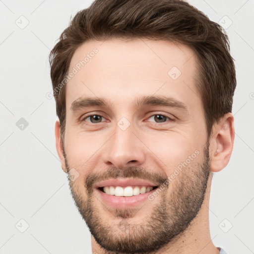 Joyful white young-adult male with short  brown hair and grey eyes