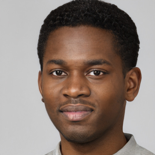 Joyful black young-adult male with short  brown hair and brown eyes