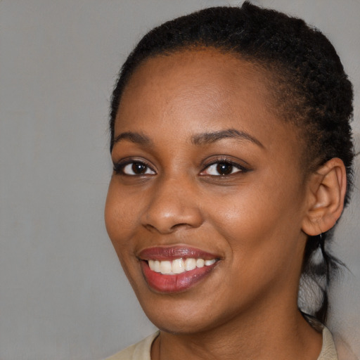 Joyful black young-adult female with short  brown hair and brown eyes