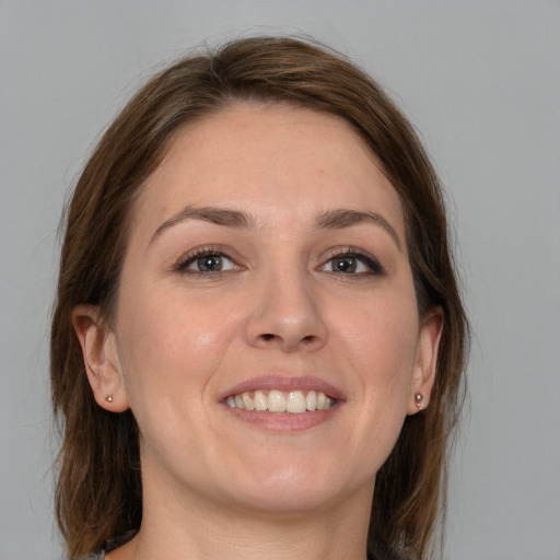 Joyful white young-adult female with medium  brown hair and grey eyes