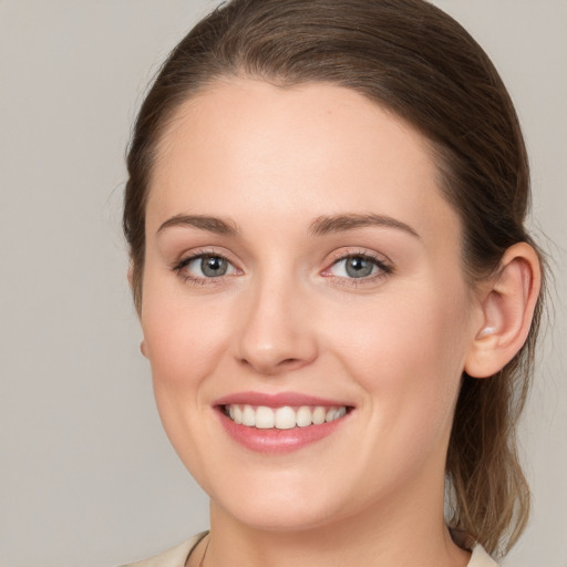 Joyful white young-adult female with medium  brown hair and grey eyes