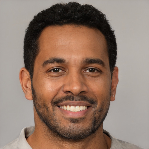 Joyful black young-adult male with short  black hair and brown eyes
