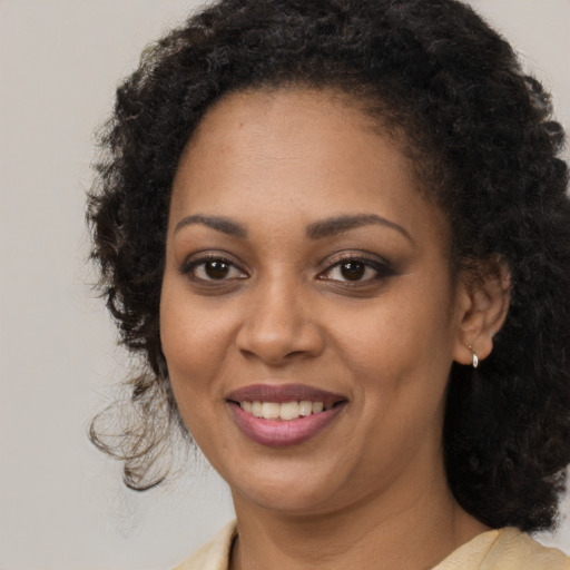 Joyful black young-adult female with long  brown hair and brown eyes
