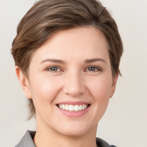 Joyful white young-adult female with short  brown hair and grey eyes