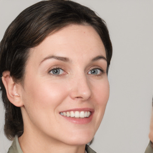 Joyful white young-adult female with medium  brown hair and grey eyes